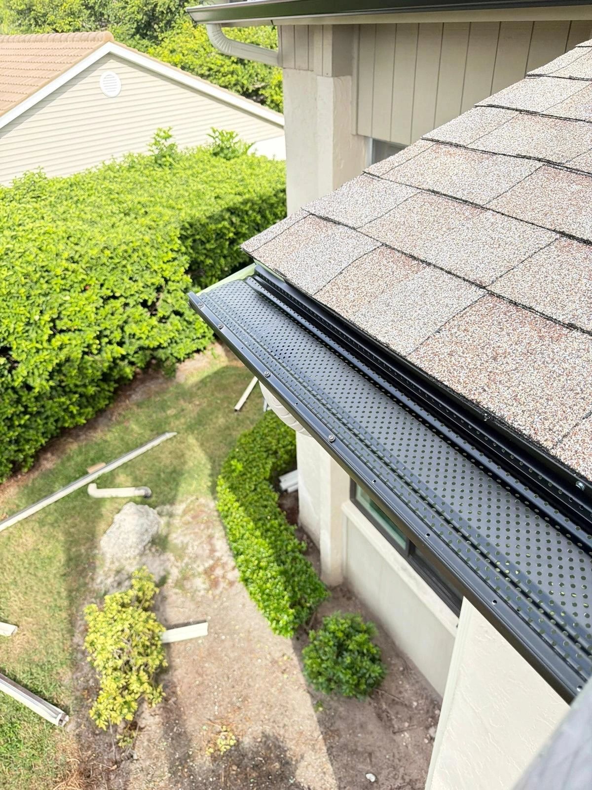 Perforated gutter guard beside a shingle roof